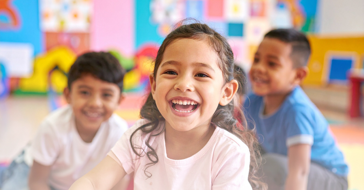 Children in classroom setting laughing.